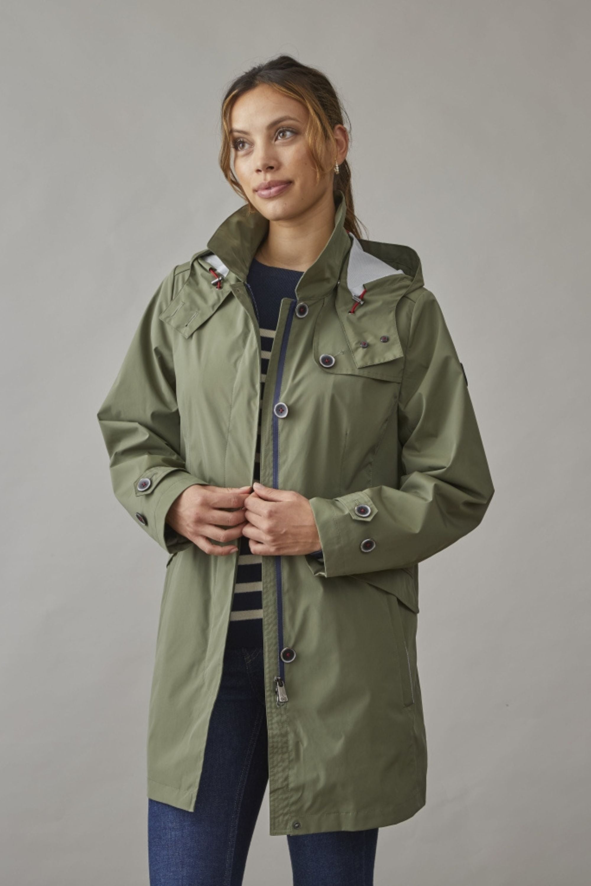 Woman wearing an olive long spring jacket with a hood, perfect for unpredictable weather. A stylish and functional choice for spring.
