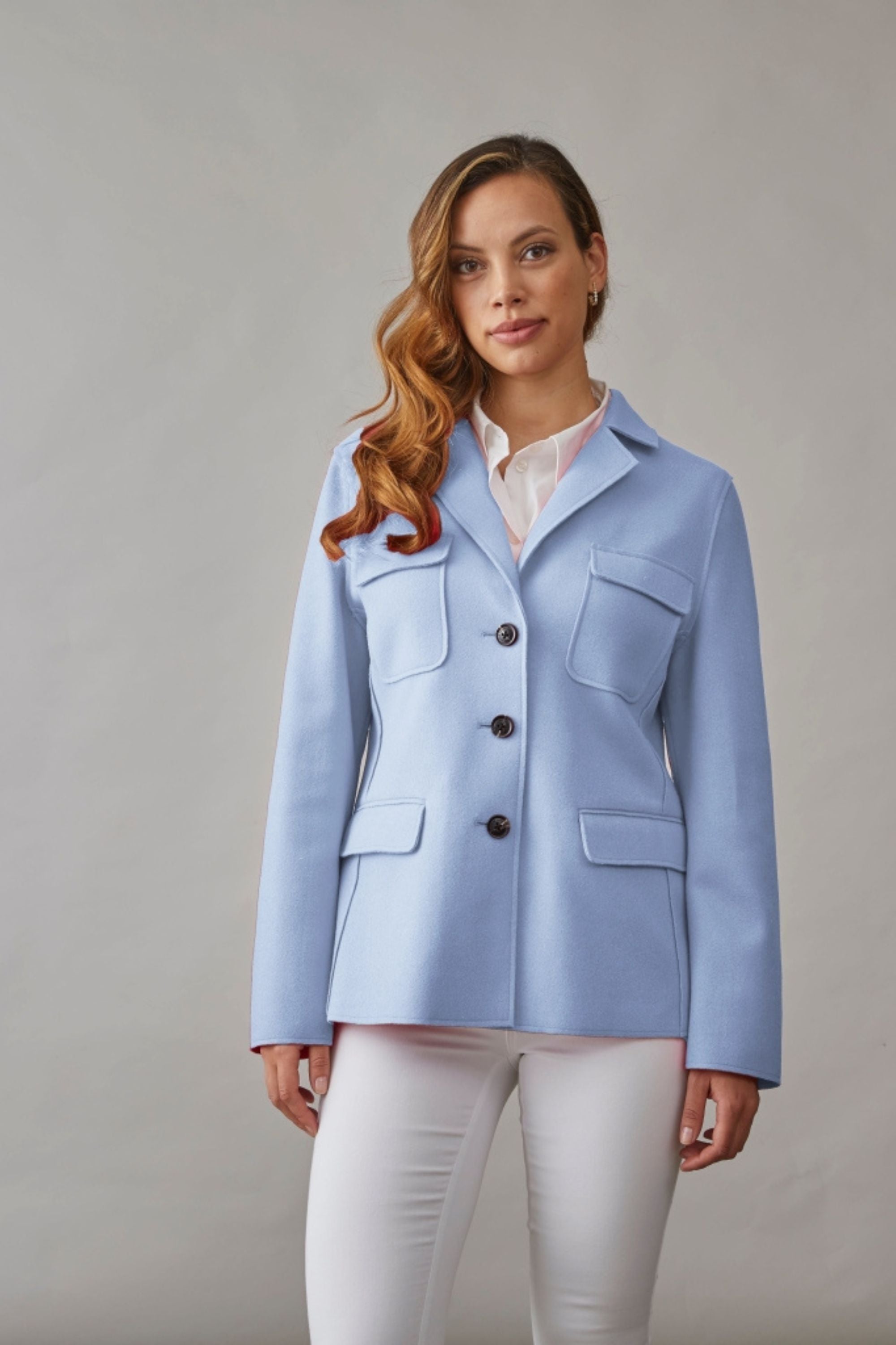 Woman wearing a tailored short spring jacket in pastel blue, styled with a white blouse and pants for a fresh seasonal look.