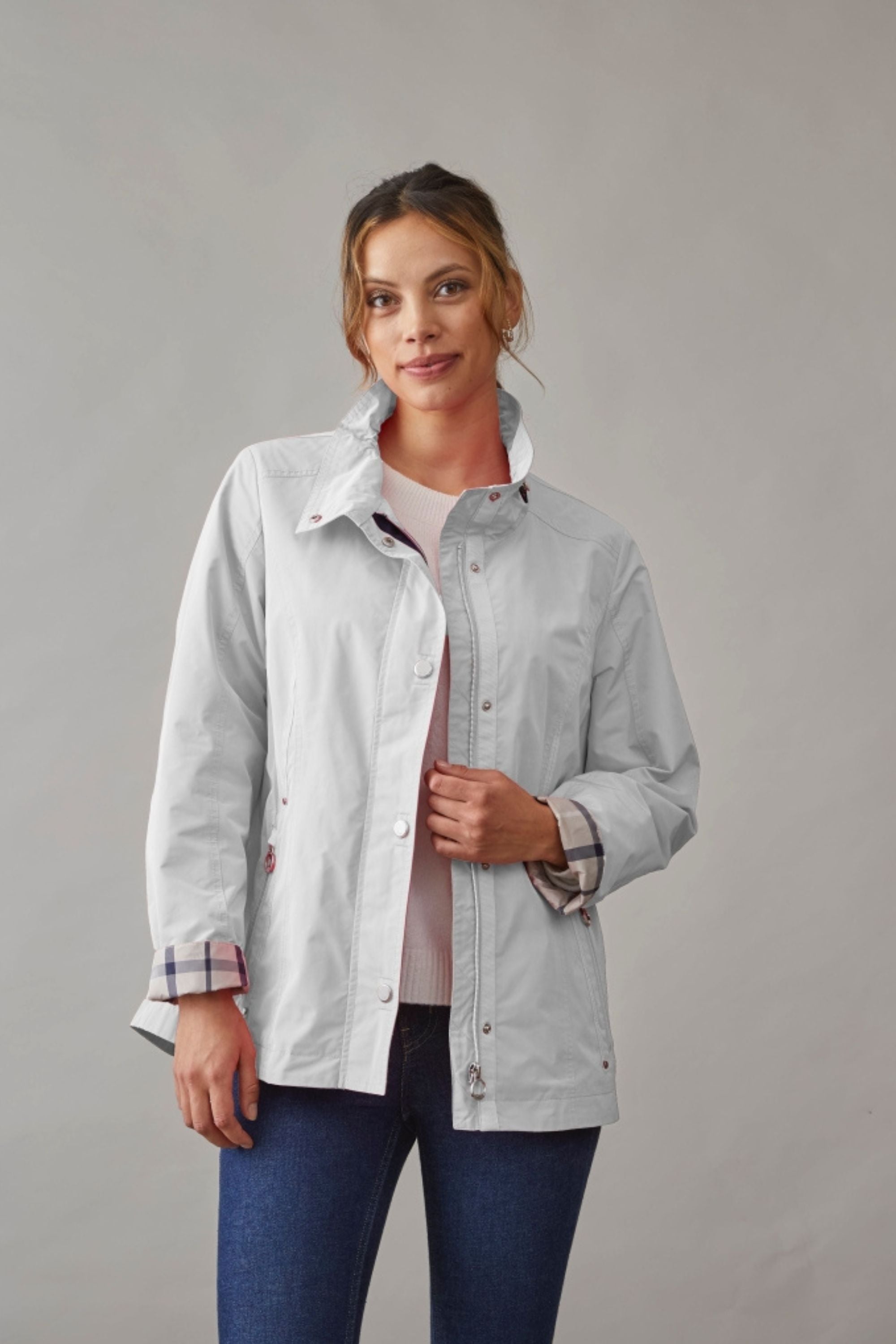 Woman wearing a stylish light spring jacket for women in off-white, featuring a relaxed fit and plaid cuffs for a casual spring look.