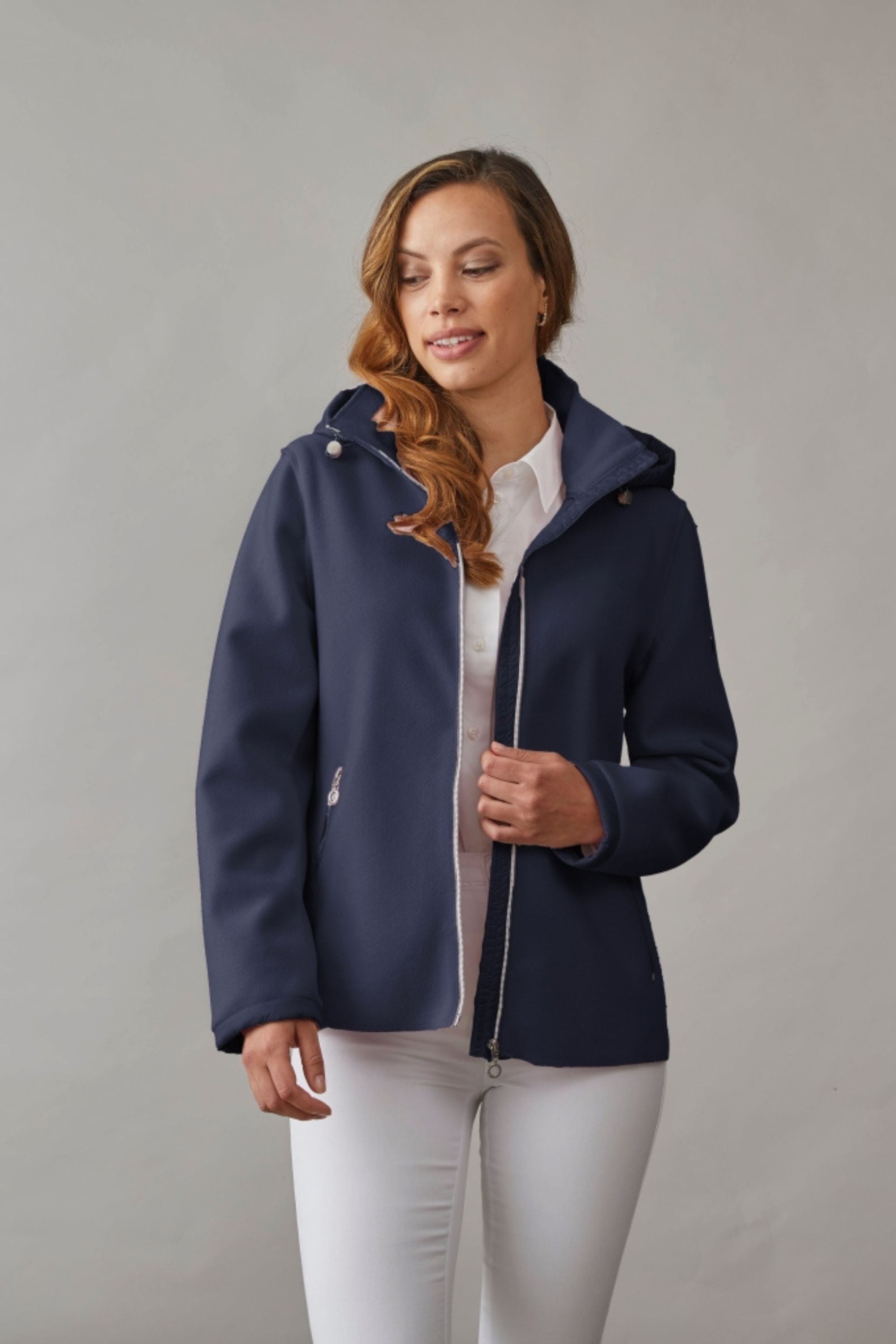Woman wearing a navy hooded spring jacket with soft fabric and a modern fit, styled with a white shirt and pants for a fresh look.